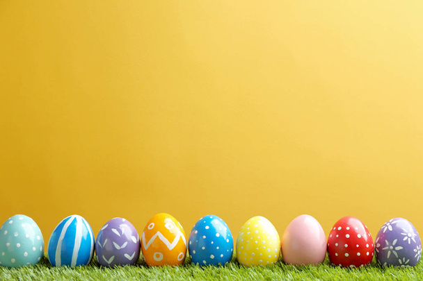 Painted Easter eggs on green grass against color background, space for text - Fotó, kép