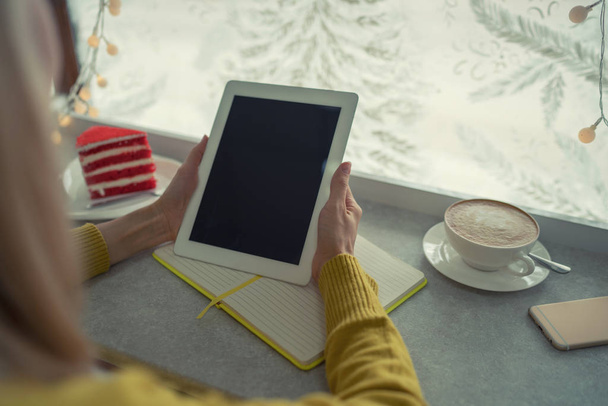 Przycięte widzenia gospodarstwa kobiece nowoczesny tablet podczas wyszukiwania przydatne informacje w Internecie i przydatne notatek zapisywanie ich do notebooka. Selektywny fokus na rękę z touch pad urządzenia - Zdjęcie, obraz