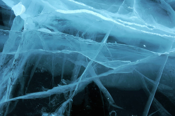 Les rayons du soleil sont réfractés par la glace transparente du lac Baïkal. fissures à différentes profondeurs créent une toile bizarre
 - Photo, image