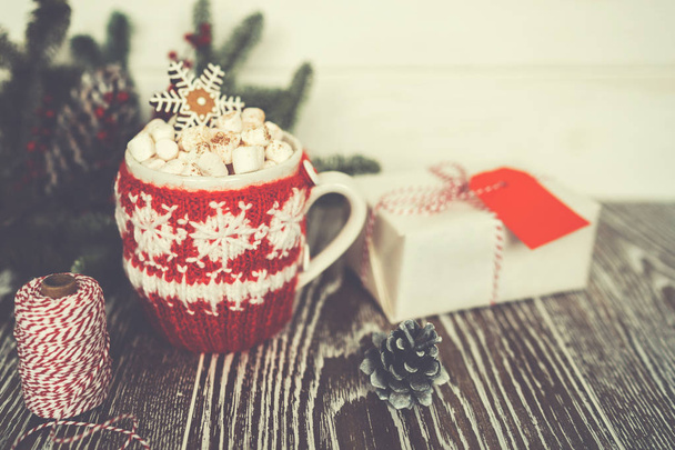 Cup of hot cocoa with marshmallows and gingerbread in the form of snowflakes against rustic background with Christmas fir branches of bokeh. Perfect winter time treat. Toned image. Soft focus. - Photo, image
