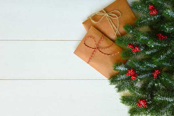 Christmas gifts, pine branches, red berries on white background. Flat lay, top view. Copy space. - 写真・画像