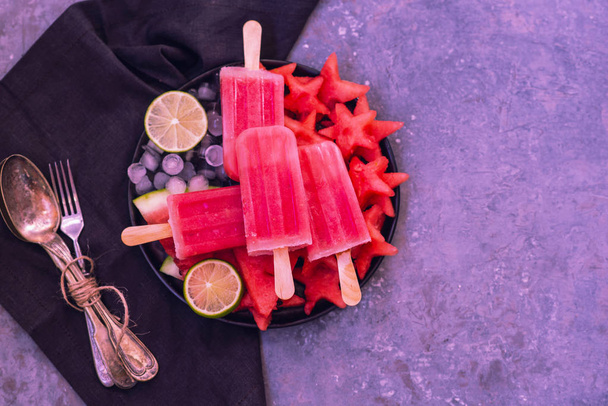 Homemade watermelon popsicles with ice against a vintage tray background. - Foto, Bild