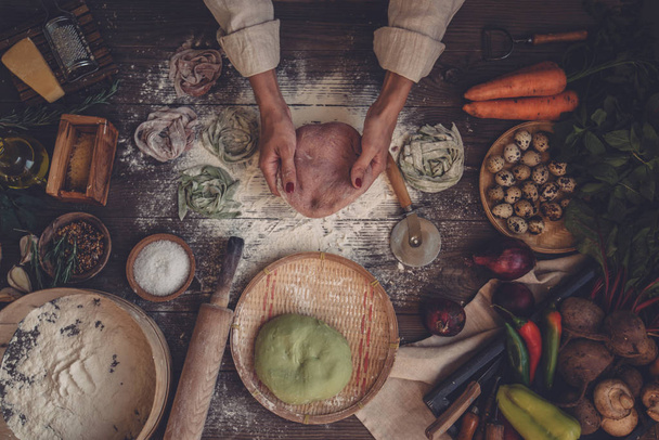 小麦粉、ローリングピン、野菜を使った素朴なキッチンテーブルに自家製パスタリンギンを作ります。素朴なスタイル、トーンのイメージ. - 写真・画像