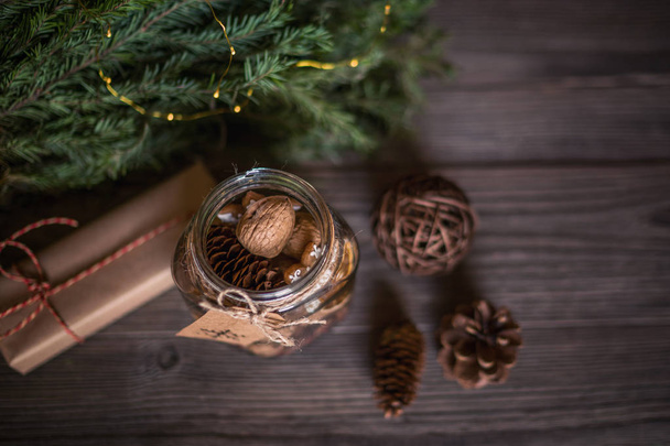 Christmas gift with homemade gingerbread cookies, nuts and chocolates. Glass jar, fir branches, Christmas spices and decor. Winter holidays, New Year or Christmas concept. Top view with copy space. - Photo, image