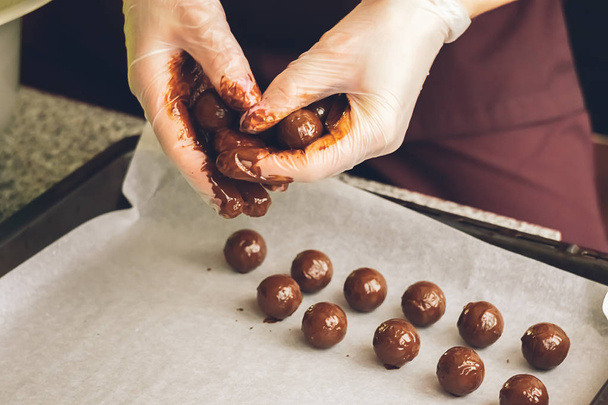 Käsintehtyjä suklaita. Pyöreät suklaat, joissa on nestemäistä suklaata pöydän pinnalla. Valikoiva painopiste
. - Valokuva, kuva