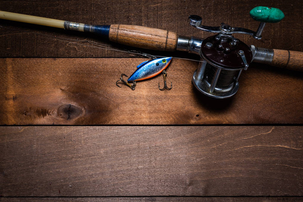 Une canne à pêche vintage et bobine sur un fond de planche en bois
 - Photo, image