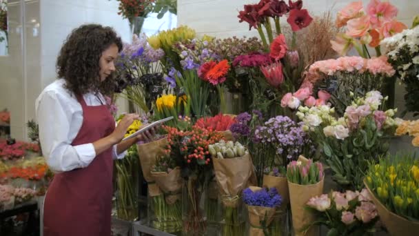 Blumenhändler prüft Preise mit Tablet im Blumenladen - Filmmaterial, Video