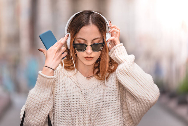Beautiful young girl listens music while walking - Fotoğraf, Görsel