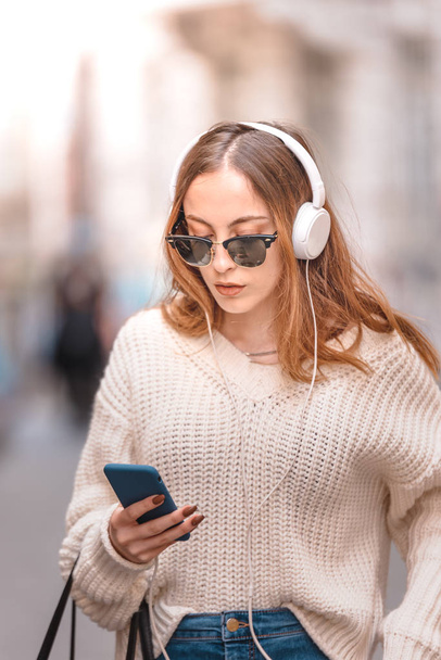 Красивая молодая девушка слушает музыку во время ходьбы
 - Фото, изображение