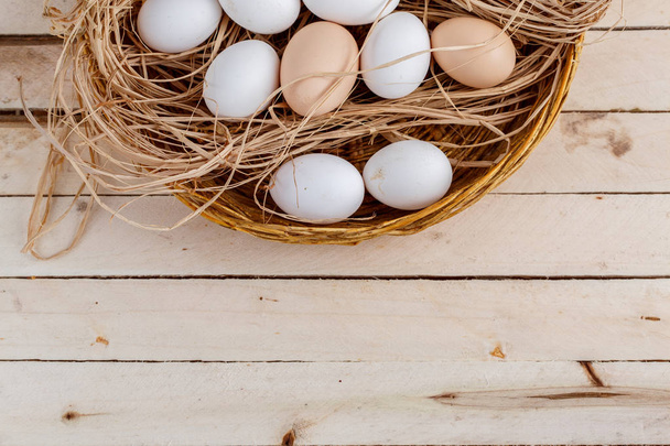 raw eggs in the hay on a wooden background - Фото, зображення