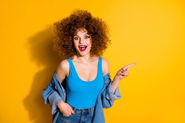 Portrait of her she nice cute charming attractive cheerful amazed astonished glad wavy-haired girl pointing forefinger aside cool ad feedback tips isolated over bright vivid shine yellow background - 写真・画像