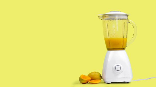 jugo de mango con una licuadora, aislado sobre un fondo amarillo
 - Foto, imagen