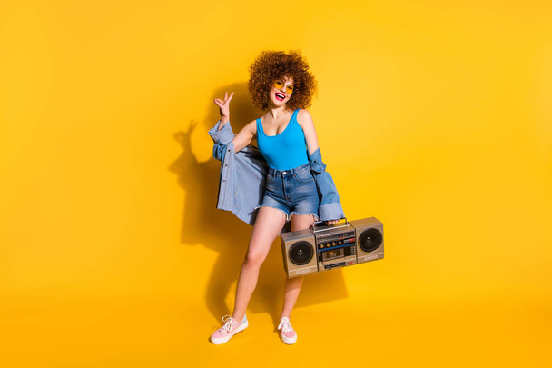 Full length body size photo beautiful she her lady wavy styling curls old-fashioned tape recorder show v-sign wear specs casual jeans denim shirt shorts tank top clothes isolated yellow background - Valokuva, kuva