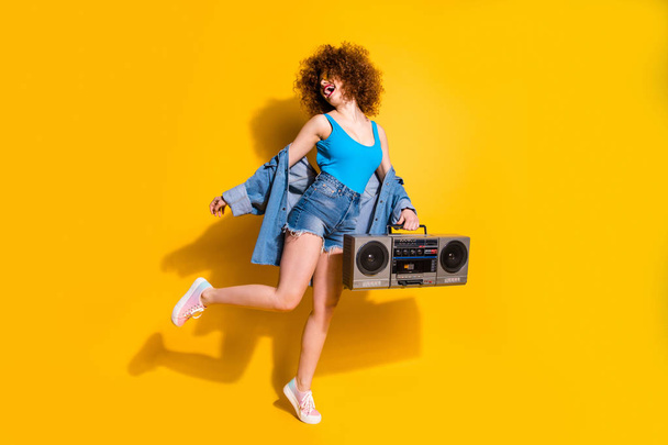 Full length body size photo beautiful she her lady wavy styling curls old-fashioned tape recorder dancing excited wear specs casual jeans denim shirt shorts tank top clothes isolated yellow background - Фото, зображення
