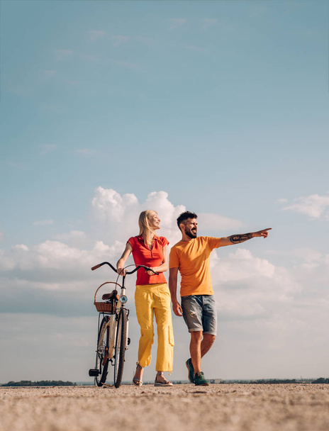 The concept of love and lifestyle. Sexy woman with vintage bike in a country road. Adventure and vacations concept. Smiling couple having fun over sky background. - Fotografie, Obrázek