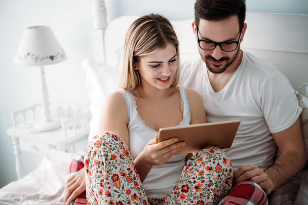 Young happy couple using tablet in bedroom - Foto, imagen