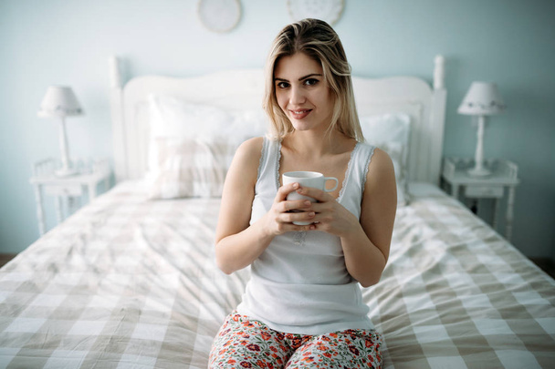 Young beautiful woman sitting on bed at home alone - Φωτογραφία, εικόνα