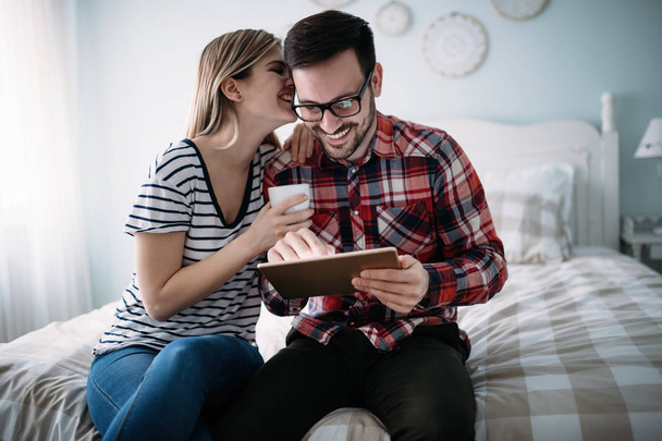 Young happy couple using tablet in bedroom - Foto, afbeelding
