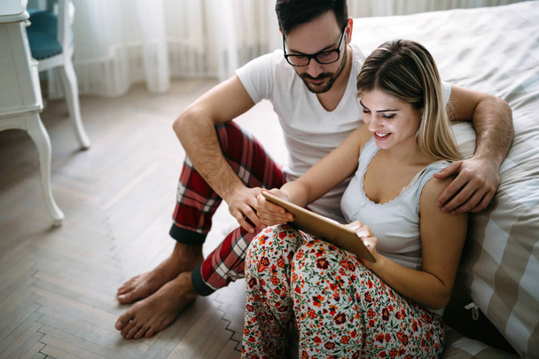 Young happy couple using digital tablet in bedroom - Фото, зображення