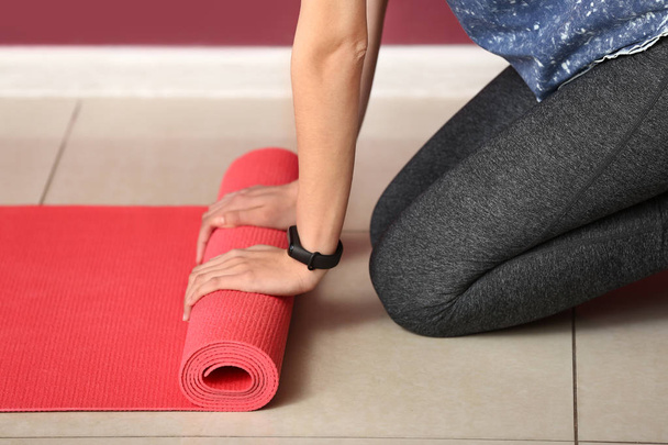 Young sporty woman with yoga mat in gym - Фото, зображення