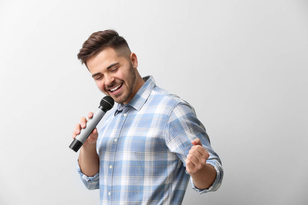 Красива співачка чоловічої статі з мікрофоном на світлому фоні
 - Фото, зображення