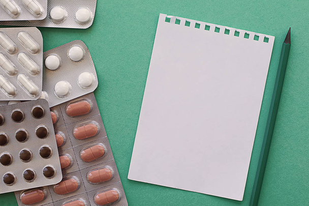pills in packs and empty prescription on green background - Fotó, kép