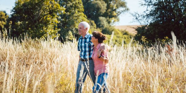 Мужчина и женщина старшего возраста наслаждаются собой и прогуливаются на природе
 - Фото, изображение