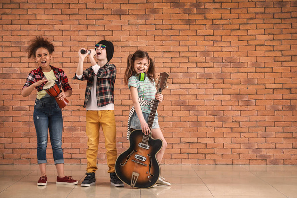 Banda de pequenos músicos contra a parede de tijolos
 - Foto, Imagem