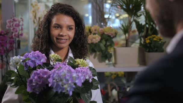 Young florist advising buyer flowering plant - Footage, Video