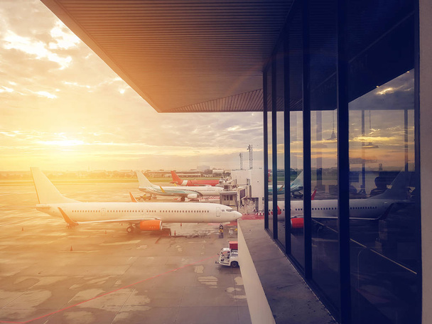 airplane at the airport terminal gate, modern international airport during sunset. transportation by plane and travel concept - Foto, imagen