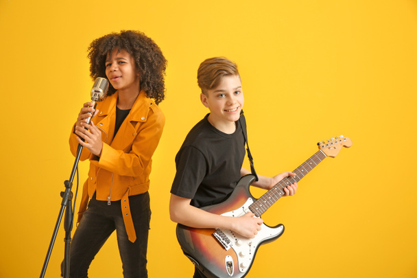 Teenage musicians playing against color background - Фото, изображение