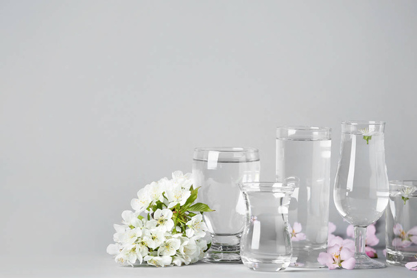 Glasses with water and flowers on table - Foto, imagen