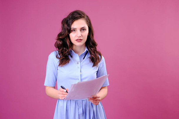 Portrait of woman with a paper and pen, making the list and thinking over pink background - Foto, immagini