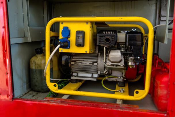消防車のグローブコンパートメントに立っている黄色いハウジングのガソリン用発電機. - 写真・画像
