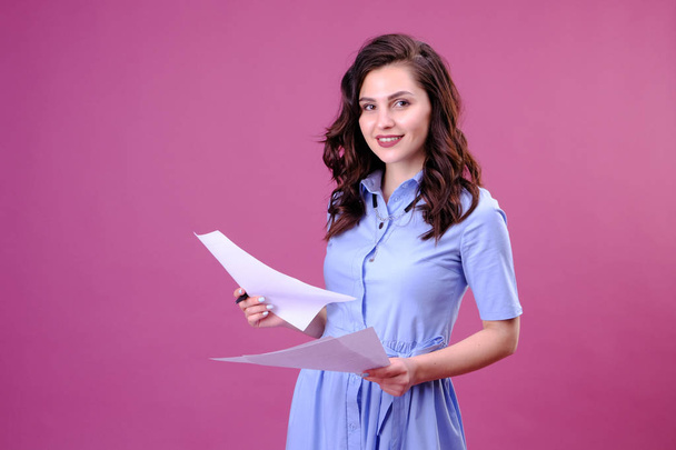 Portrait of happy woman with a paper and pen, making the list and thinking over pink background - Fotó, kép