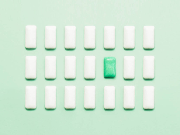 One green chewing gum  standing out of white chewing gums - Photo, Image