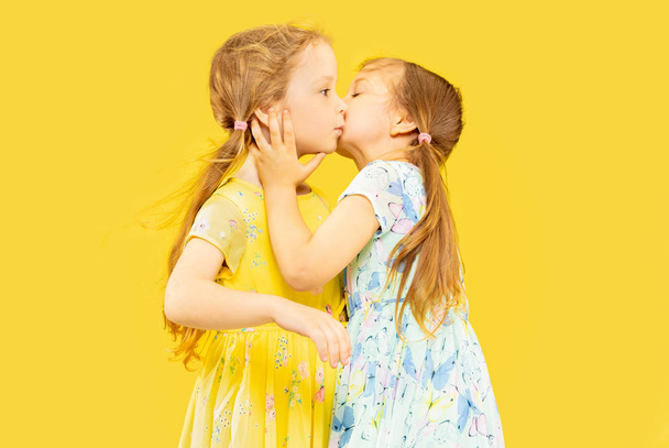 Beautiful emotional little girls isolated on yellow background - Foto, Imagem