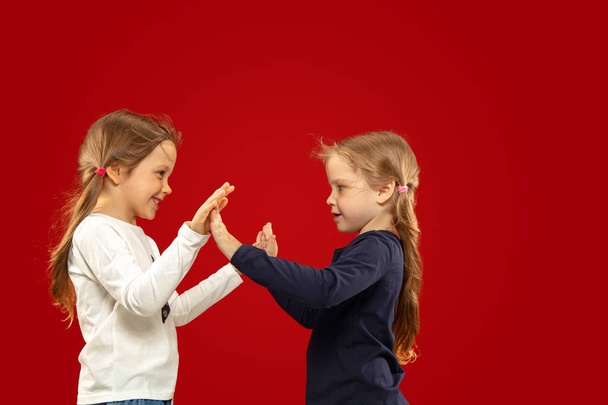 Beautiful emotional little girls isolated on red background - Photo, image