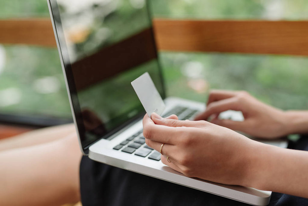 Kredi kartı tutan ve dizüstü bilgisayar kullanan bir kızın portresi. İnternetten alışveriş - Fotoğraf, Görsel