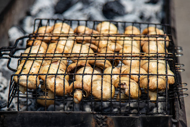 mouth-watering, yummy barbecue grill on the nature. Vegetarian vegetables chopped hot  mushrooms in a metal grid cooking on a portable brazier outdoor in sunny day close up - Foto, immagini