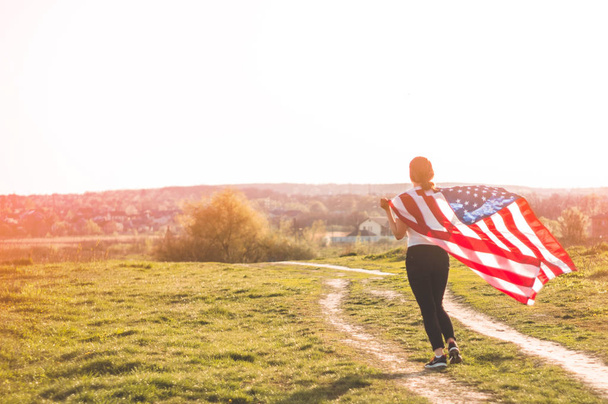 Women running in the field with American flag USA celebrate 4th of July - 写真・画像