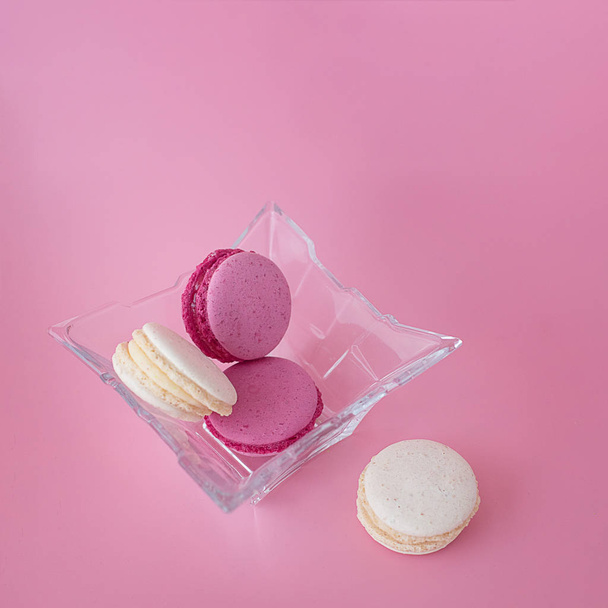 several multi-colored macarons in a glass plate on a square pink - Foto, Imagem