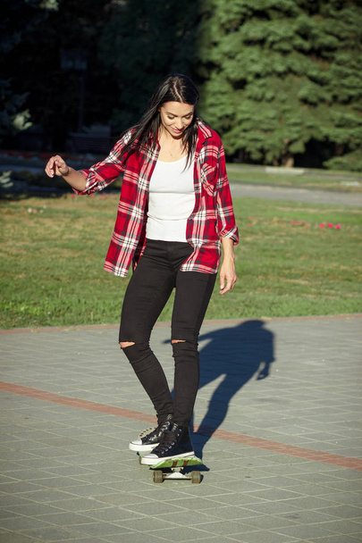 Beautiful woman with a skateboard on the street - Foto, Imagem