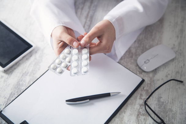 Bělošský doktor drží ve stole pilulky. Medicína - Fotografie, Obrázek