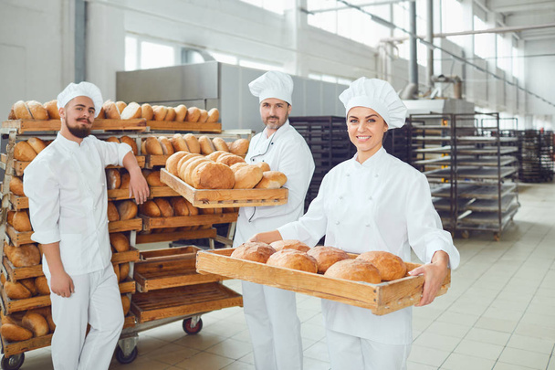 Bakers hold a tray with fresh bread in the bakery. - Valokuva, kuva