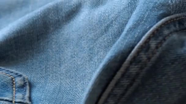 Crumpled blue jeans laying on the desk, close shot. Blurred background. Selective soft focus. Camera moving along seams and rear trouser pocket. Background for fashion banners and wallpapers. - Záběry, video