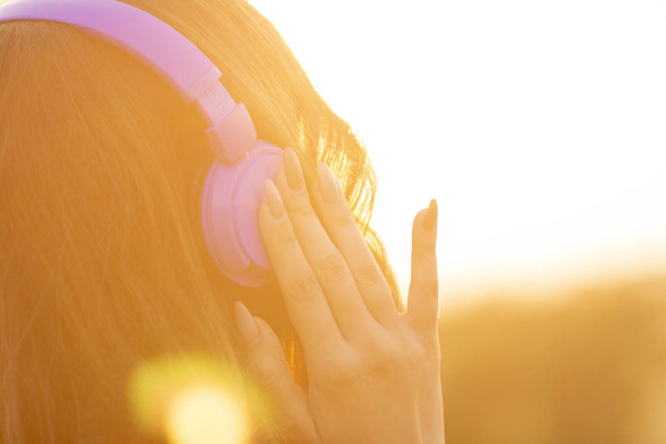 teenager girl in headphones listening to music on nature, young woman is relaxing in the summer field - Fotó, kép