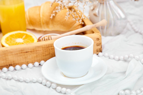 Hyvää huomenta. Mannermainen aamiainen valkoisilla lakanoilla. Kuppi kahvia, appelsiinimehua, croissantteja, hilloa puutarjottimella ylhäältä. Huippunäkymä. Litteä pano. Kopioi tilaa. Hotellihuone aikaisin aamulla
  - Valokuva, kuva