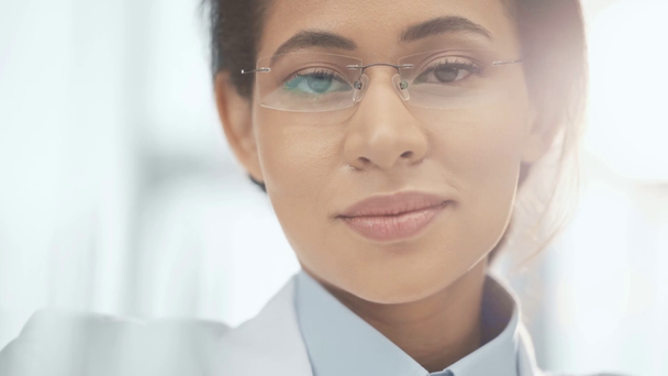 retrato de sonriente médico afroamericano en gafas mirando a la cámara
 - Imágenes, Vídeo