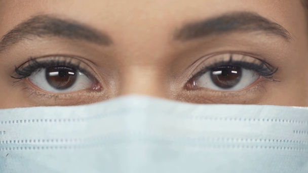 közelről kilátás afroamerikai nő az orvosi maszk villog, miközben nézi kamera - Felvétel, videó
